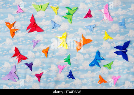 Colourful Origami paper butterflies on a cloudy sky pattern background Stock Photo