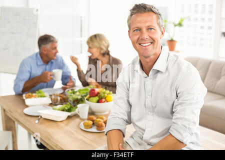 Smiling casual businessman sitting on table at lunch Stock Photo