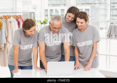 Smiling volunteers using laptop together Stock Photo