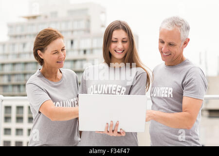 Smiling volunteers using laptop together Stock Photo