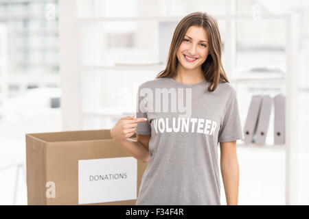 Smiling brunette volunteer showing her shirt Stock Photo