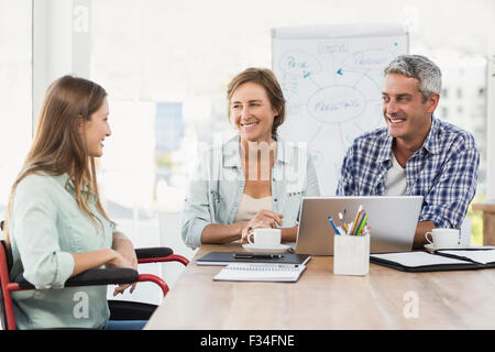 Casual businesswoman in wheelchair talking to colleagues Stock Photo