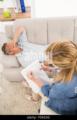 Depressed man lying on couch and talking to therapist Stock Photo