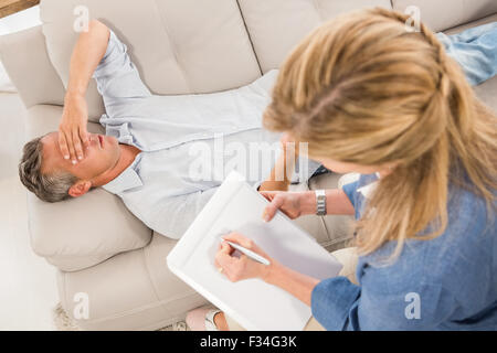 Depressed man lying on couch and talking to therapist Stock Photo
