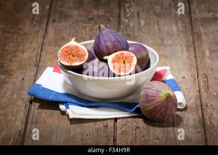 fresh figs in a bowl on dish towel on rustic wooden table Stock Photo
