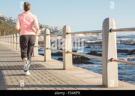 Rear view of sporty woman jogging at promenade Stock Photo