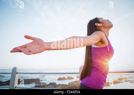 Carefree fit woman with arms outstretched at promenade Stock Photo