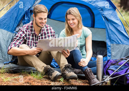 Young pretty hiker couple sitting in a tent looking at map Stock Photo