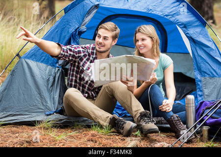 Young pretty hiker couple sitting in a tent pointing Stock Photo