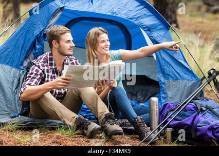 Young pretty hiker couple sitting in a tent pointing Stock Photo