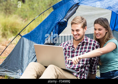 Young pretty hiker couple sitting in a tent looking at laptop Stock Photo
