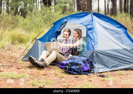 Young pretty hiker couple sitting in a tent looking at laptop Stock Photo