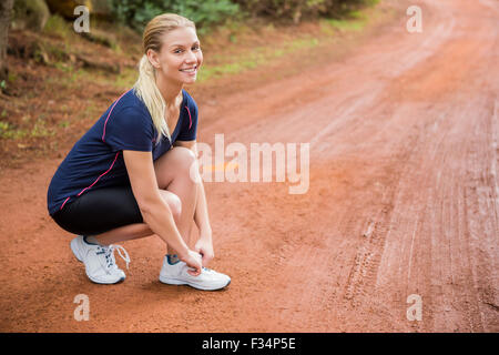 Smiling athletic blonde tying her shoelace Stock Photo
