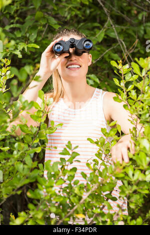 Smiling blonde looking through binoculars Stock Photo