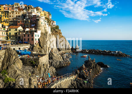 Cliffside view of Manarola village, bathers, and harbor in Italy's Cinque Terre. Stock Photo
