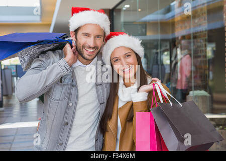 Young happy couple holding shopping bags with christmas hats on their hats Stock Photo