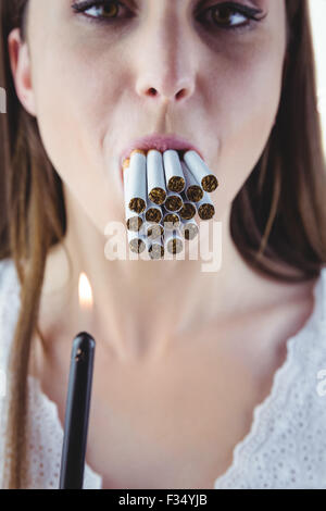 Woman lighting many cigarettes in mouth Stock Photo