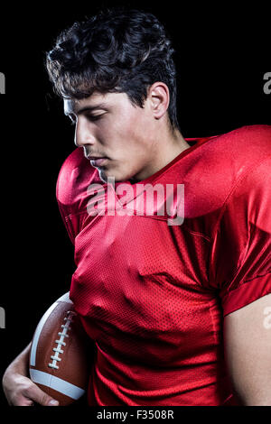 American football player holding ball while eyes closed Stock Photo