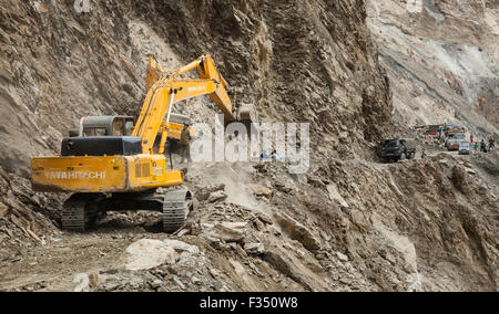 Excavator from Border Roads Organization and GREF clears hazardous Himalayan mountain road following landslide Stock Photo