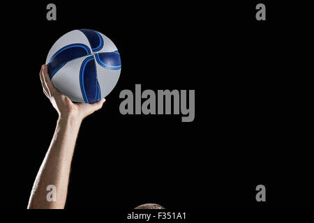 Rugby player with arm raised holding ball Stock Photo