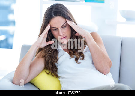 Depressed pregnant woman sitting on sofa Stock Photo