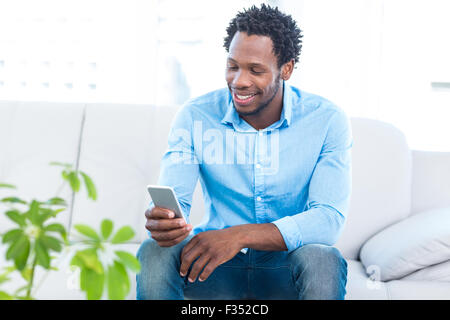 Smiling man using smartphone while sitting Stock Photo