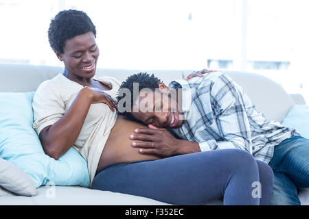 Happy pregnant woman with husband listening her belly at home Stock Photo