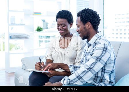 Happy man talking with pregnant wife while pointing on paper Stock Photo