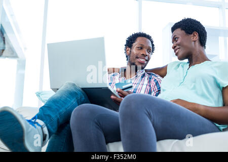 Couple smiling and sitting on sofa Stock Photo
