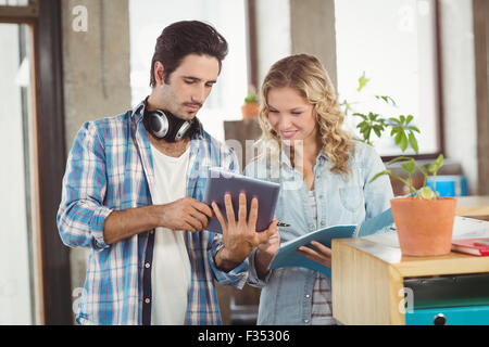 Businessman showing digital tablet to colleague in office Stock Photo