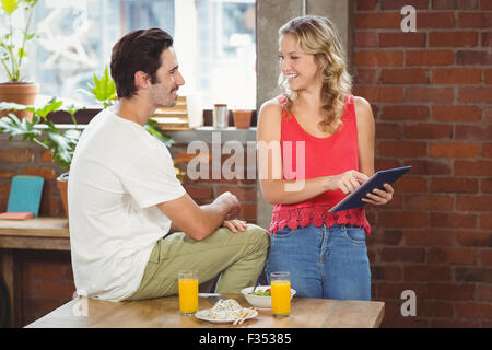 Businesswoman pointing towards digital table while looking at colleague Stock Photo