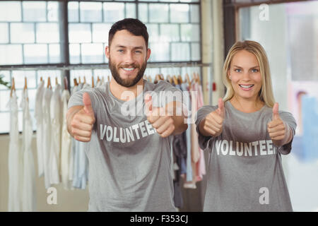 Smiling volunteers giving thumbs up Stock Photo