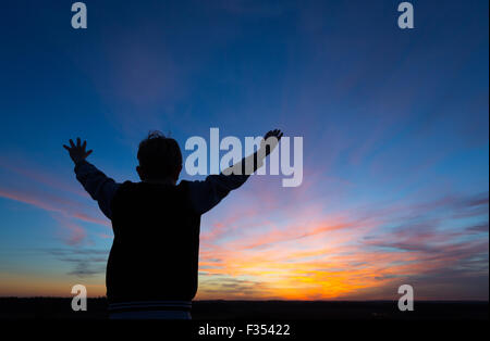 silhouette of a boy playing outside at dusk Stock Photo
