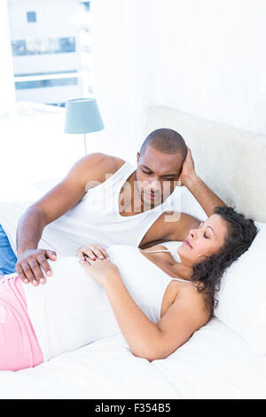 Affectionate man looking at pregnant wife sleeping on bed Stock Photo