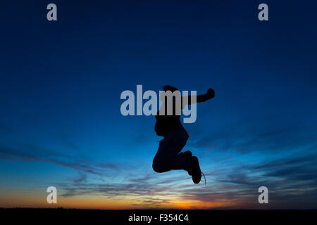 silhouette of a boy playing outside at dusk Stock Photo
