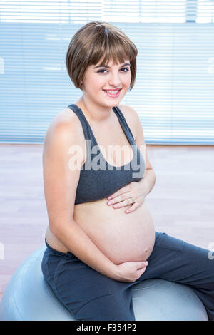 Portrait of happy pregnant woman sitting on fitness ball Stock Photo