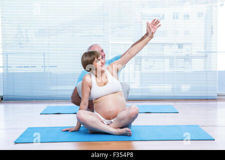 Instructor teaching yoga to pregnant woman Stock Photo