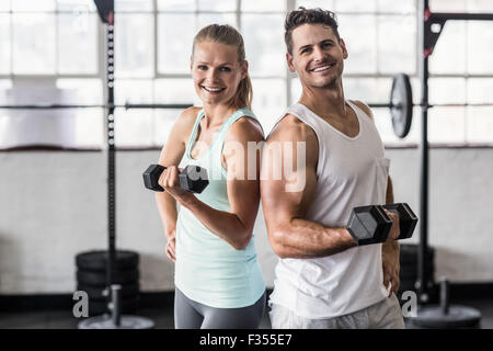 Back to back couple exercising with dumbbells Stock Photo