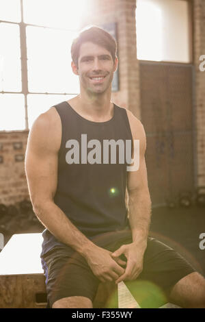Portrait of a smiling man sitting on plyo box Stock Photo