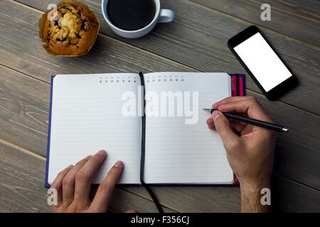 Person writing on a diary at the desk Stock Photo