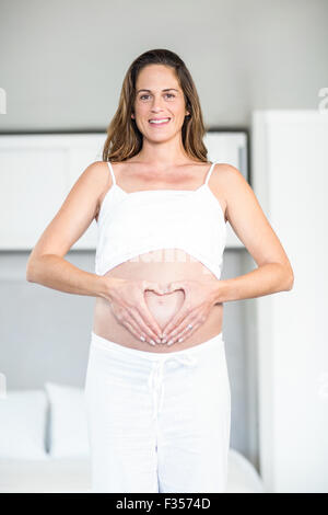 Portrait of happy woman making heart on abdomen Stock Photo