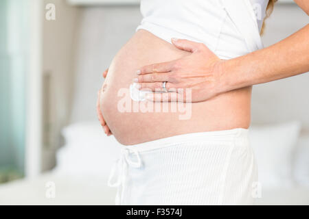 Midsection of woman applying cream on belly Stock Photo