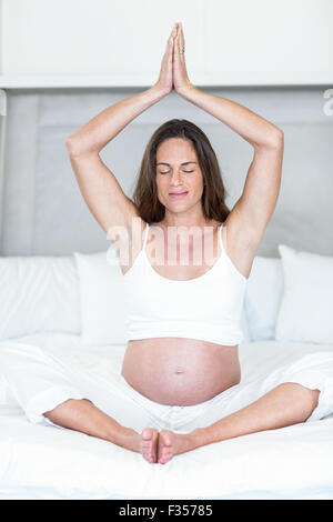 Happy woman meditating on bed Stock Photo
