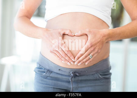 Midsection of woman hands making heart shape on belly Stock Photo