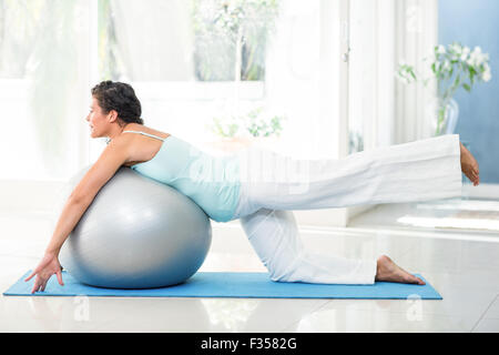 Pregnant woman exercising with ball on mat Stock Photo