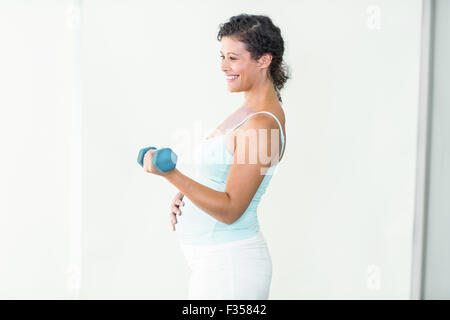 Happy pregnant woman lifting dumbbells Stock Photo