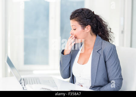 Tired pregnant businesswoman yawning Stock Photo