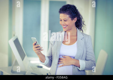 Pregnant  businesswoman using mobile phone Stock Photo