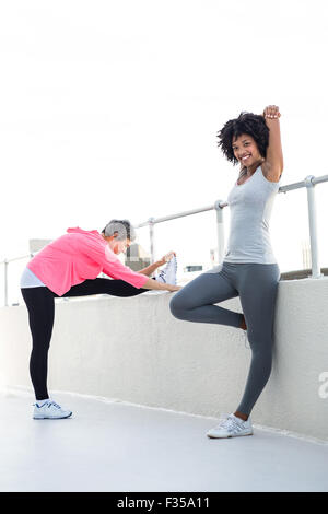 Happy young woman stretching with female friend Stock Photo
