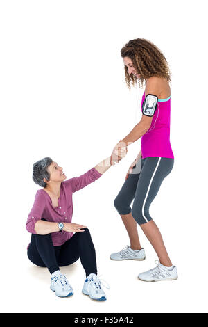 Friend assisting woman in getting up Stock Photo